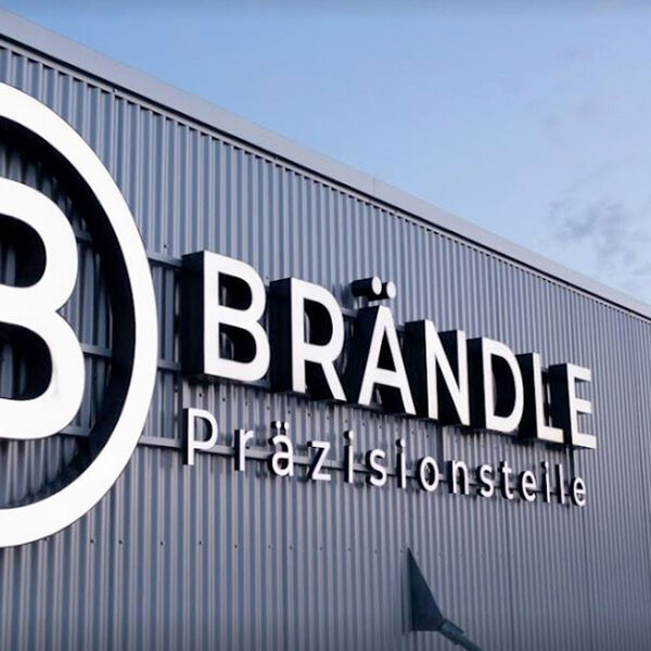 Lichtwerbung als Leuchtschrift auf Metallfassade von Industriegebäude, Motiv Brändle aus Albershausen